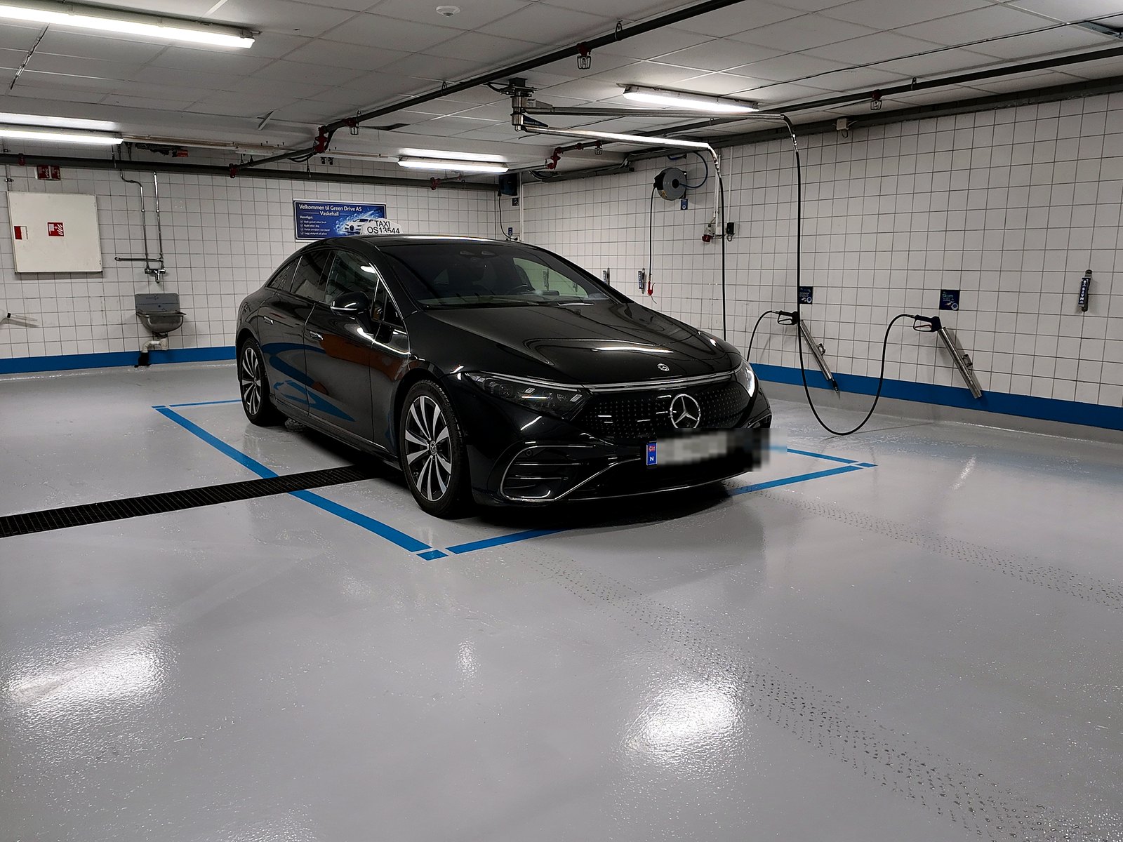 Bil som står alene på en romslig vaskeplass innendørs.